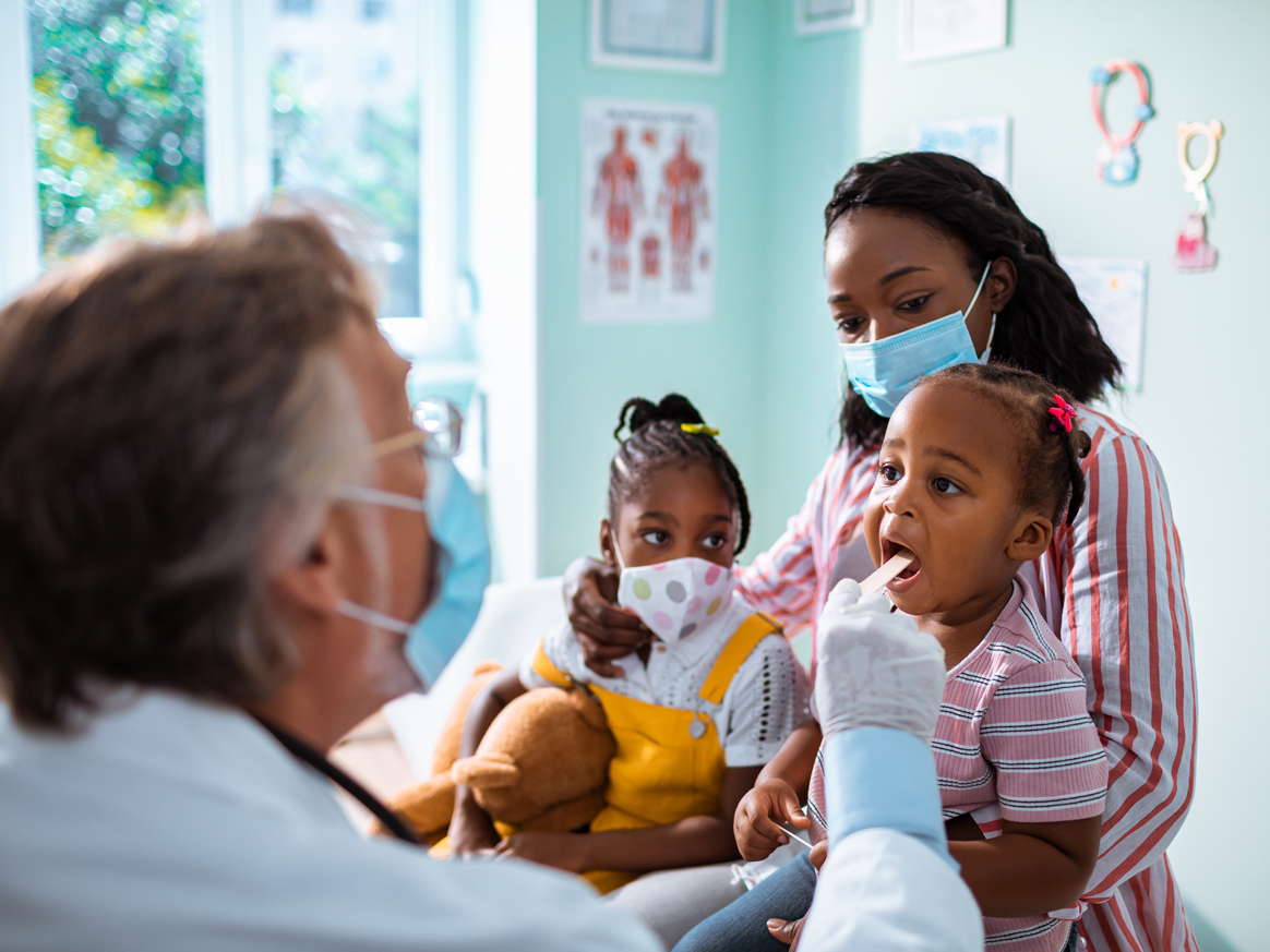 Doctor talking with a young patient and their parent.