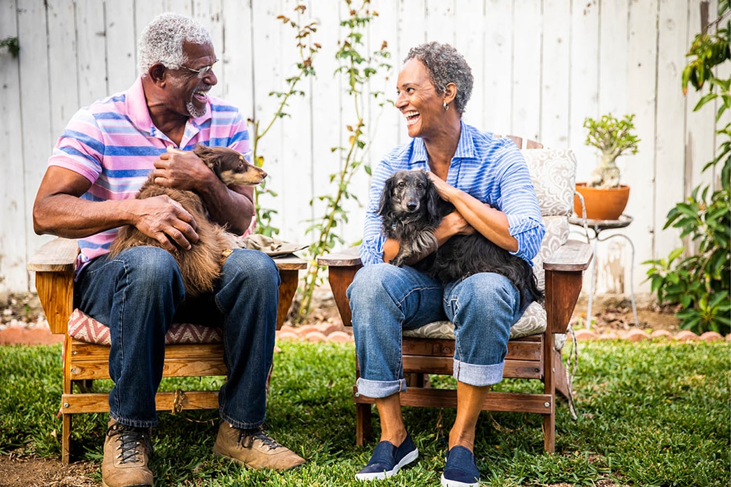 Two people holding dogs in the yard