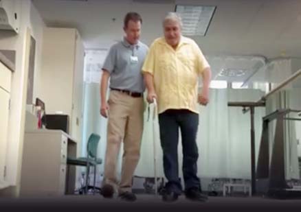 man helps patient walk with cane