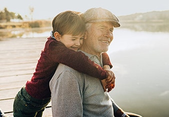 Grandson hugging grandfather by lake